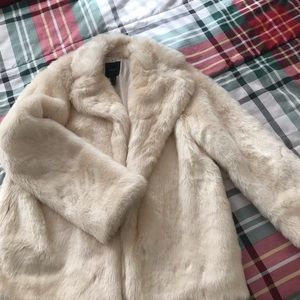 A faux fur coat ,a single snap button-front closure, and long sleeves.